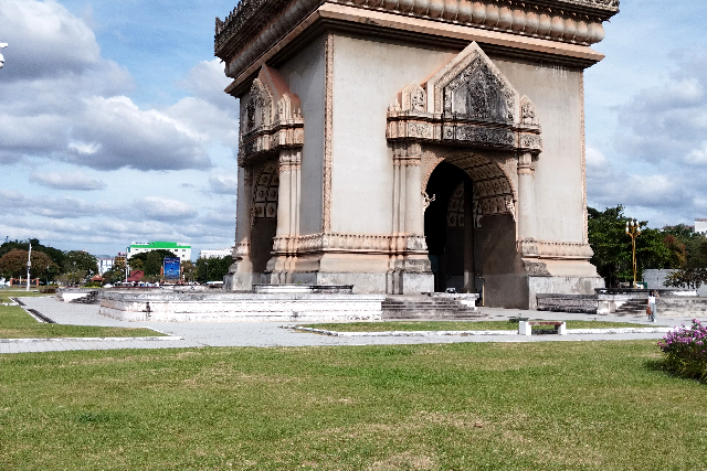 Title:『 パトゥーサイの写真(外観・内部・展望台)』画像説明 :*パトゥーサイの写真(外観・内部・展望台)*柱状のフォルムが特徴的で、どの角度から見ても 高さと存在感 を感じます*遠くから見るとほんとうに「凱旋門」のようですが、近くまでくると*仏教的な文様や彫刻 が視界に入ります*周囲にはベンチや歩道が整備されていて、散策スポットとしても心地よい空間です