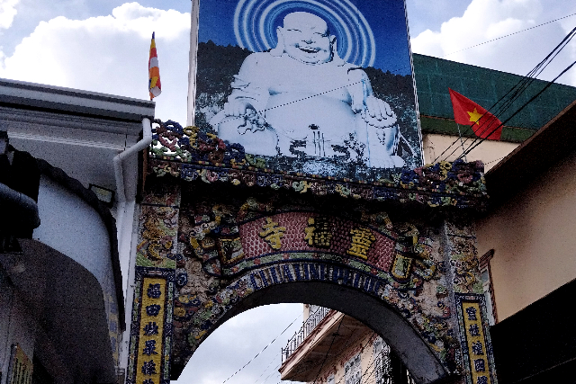 Title:『 チャイマット駅から歩いて向かう、リンフォック寺までの道のり』画像説明 :*チャイマット駅から歩いて向かう、リンフォック寺までの道のり*市場から道を隔てた反対側には漢字で書かれた文字看板が道路両脇に掲げられ、その上に布袋尊のような像が描かれた看板がありました