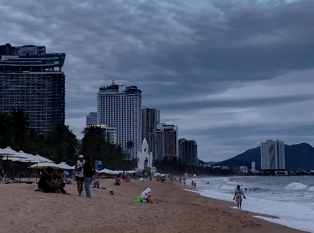 Sub_title: 夕方、傘を持って外へ| tag : ニャチャン 街歩き,ニャチャン ビーチ 場所,ニャチャン 観光,ニャチャン 行き方,| 画像説明 : _夕方、傘を持って外へ_夕方になり、雨傘を手に外へ出ることにしました_まず向かったのは海岸_空には黒い雲が広がり、今にも降り出しそうな雰囲気ですが、_それでも海岸には思ったより人の姿があります